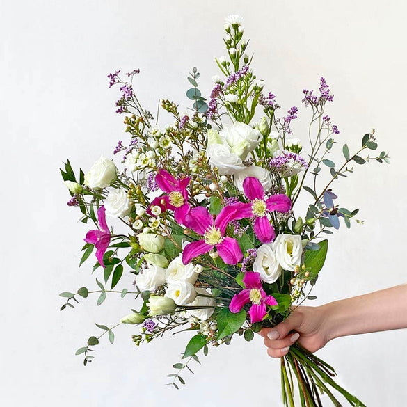 Wild garden style flower bouquet with purple clematis, white lisianthus and eucalyptus.